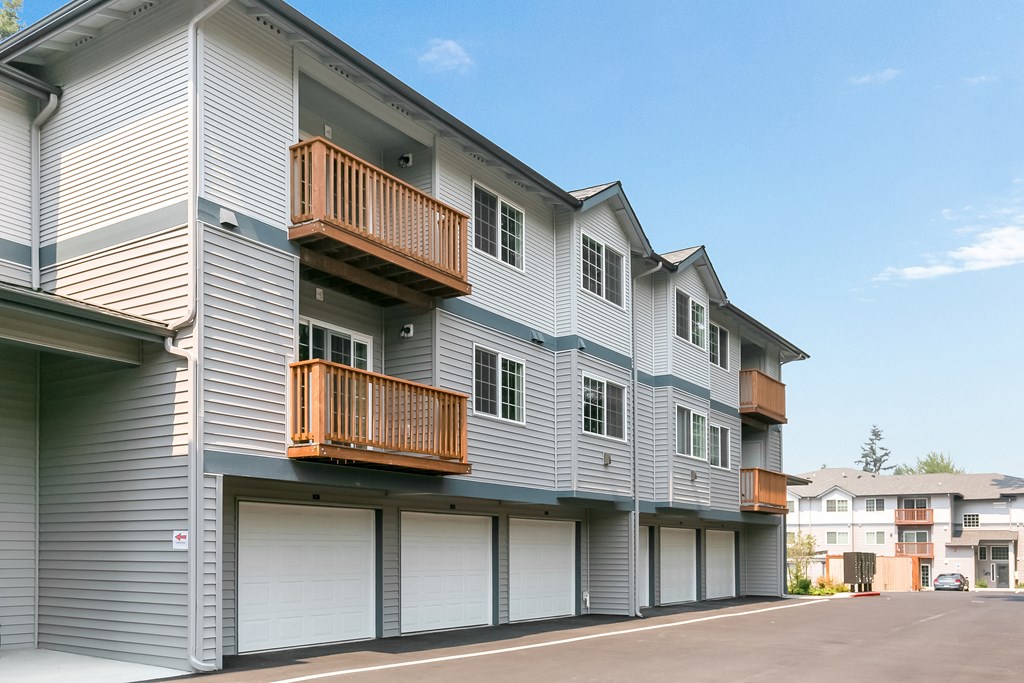 a gray apartment building with white garage doors and balconies