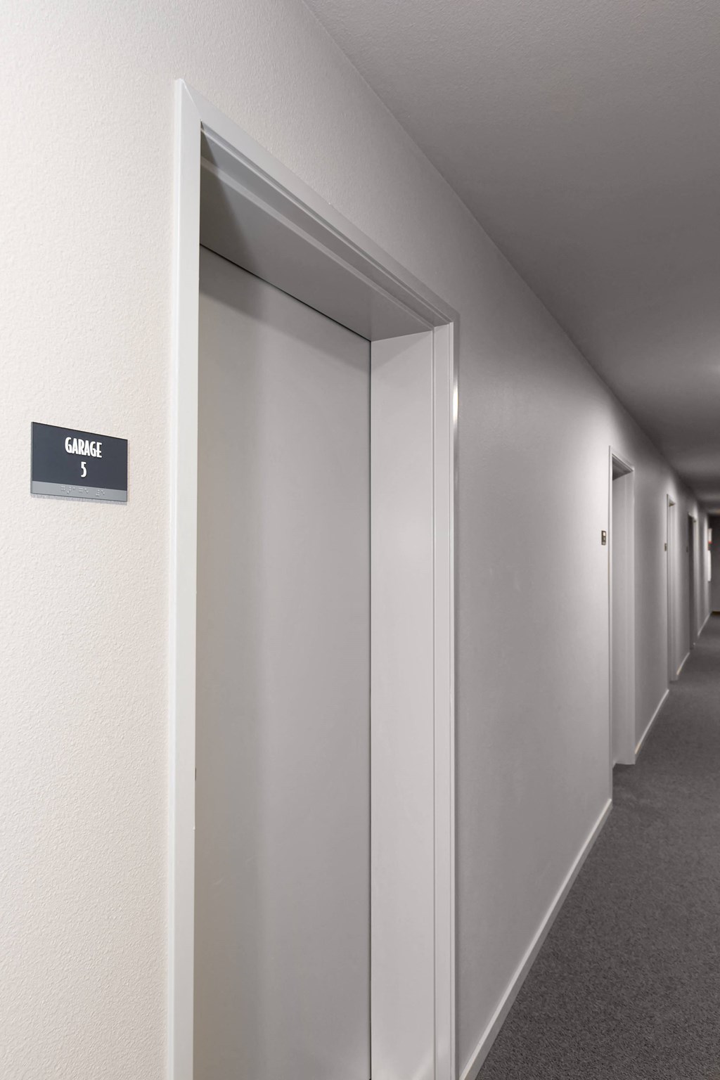 a corridor with white walls and doors and a sign on the wall