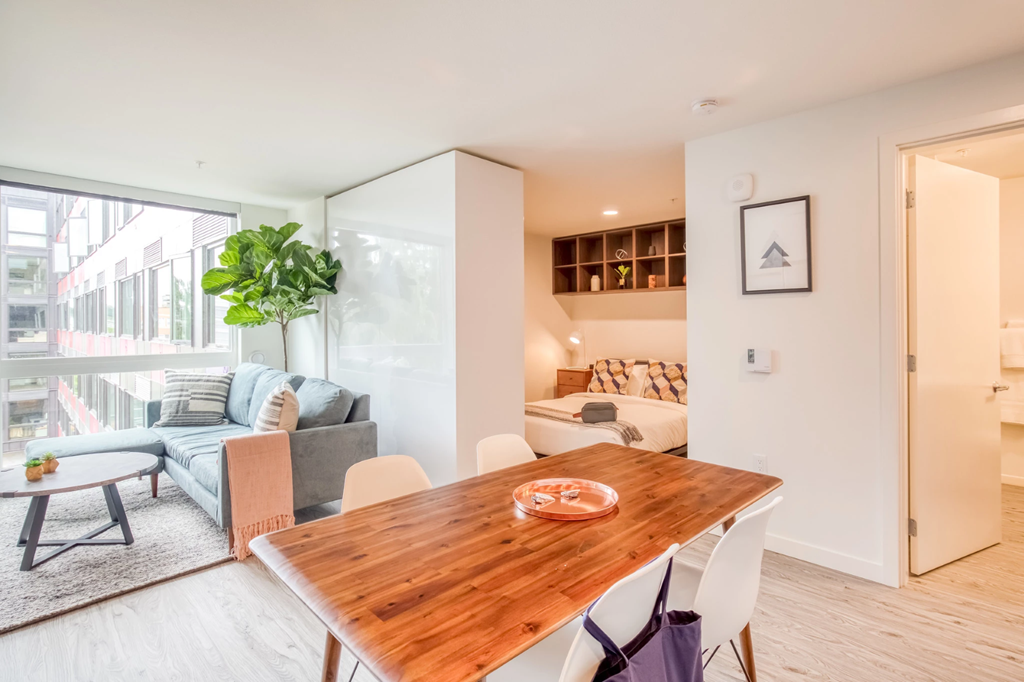 a dining area with a wooden table and a living room with a couch