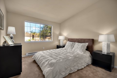 A bedroom with a large bed and two lamps.