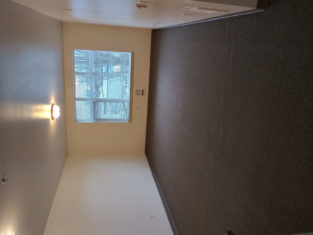 an empty room with a window and a white floor
