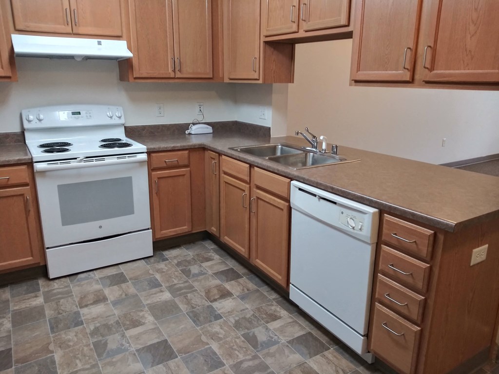 an empty kitchen with white appliances and wooden cabinets