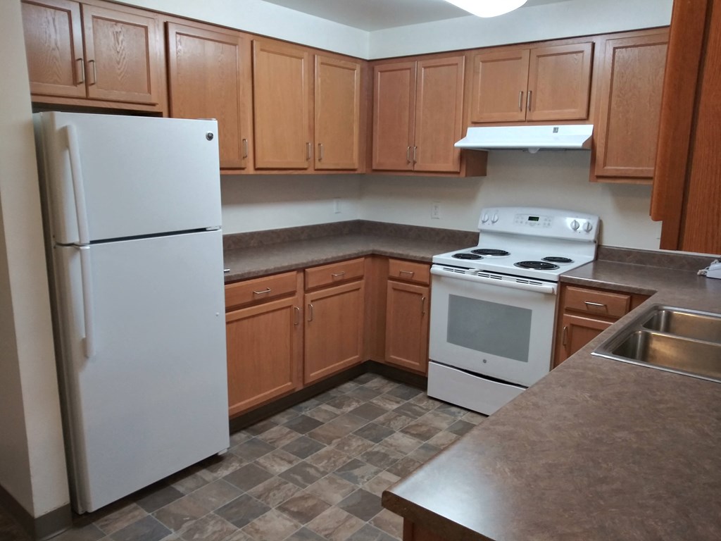 an empty kitchen with white appliances and wooden cabinets