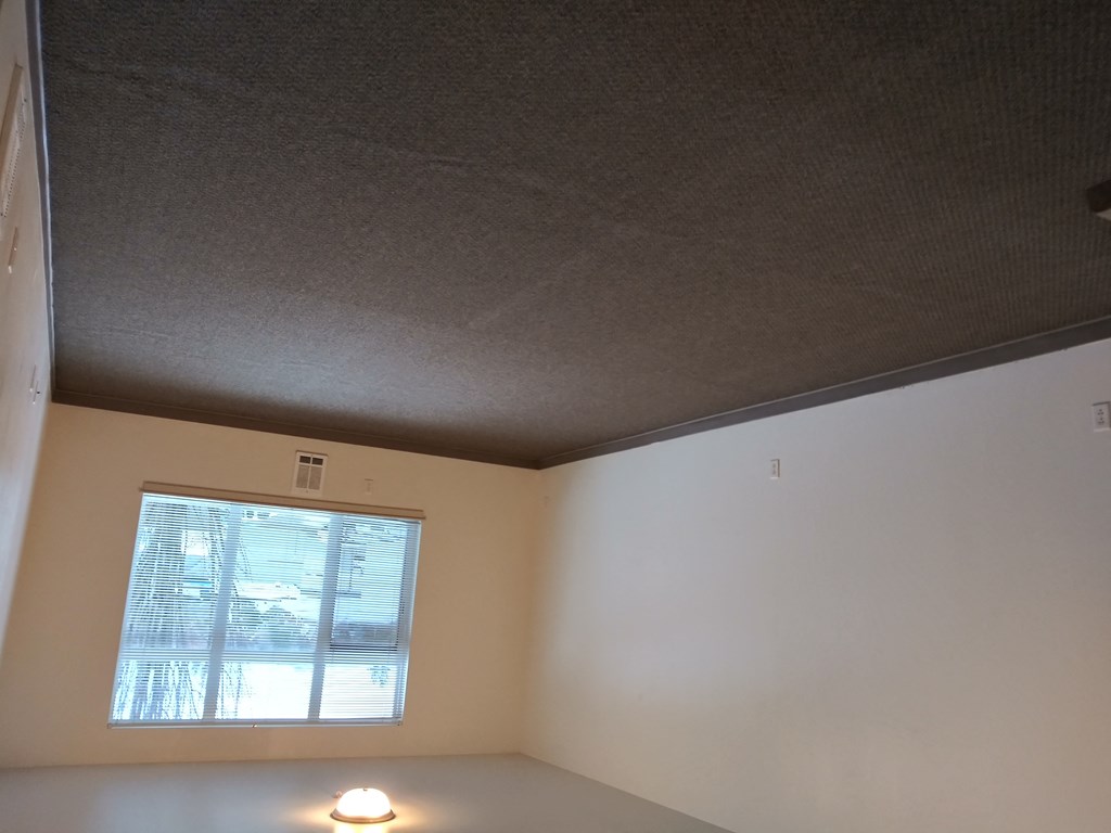 an empty room with a window and a lamp on the floor