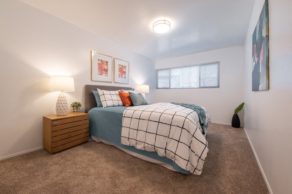 a bedroom with carpeted floors and a bed with blue and white comforter