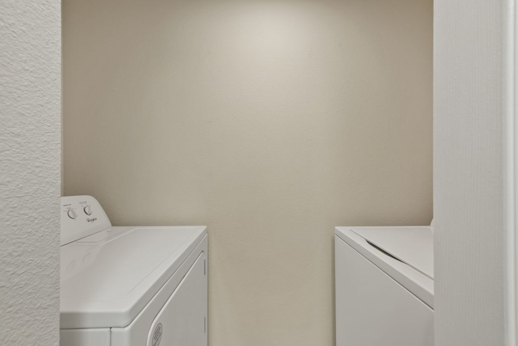 Two white washing machines in a laundry room.