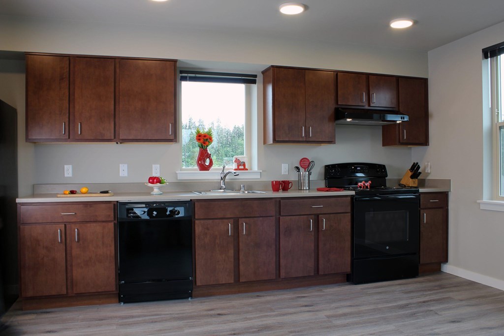 A kitchen with black appliances and wooden cabinets.
