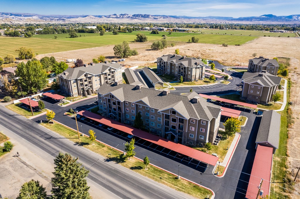 A large apartment complex with a parking lot in front.