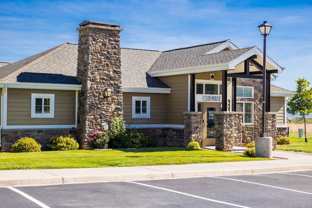 A building with a stone pillar and a sign that says "Clubhouse" in front of it.