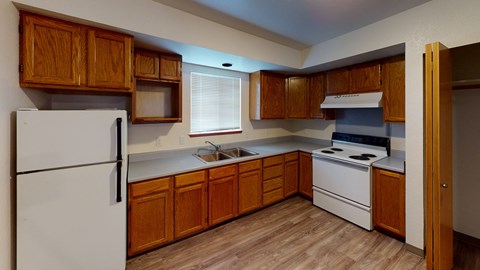 an empty kitchen with white appliances and wooden cabinets