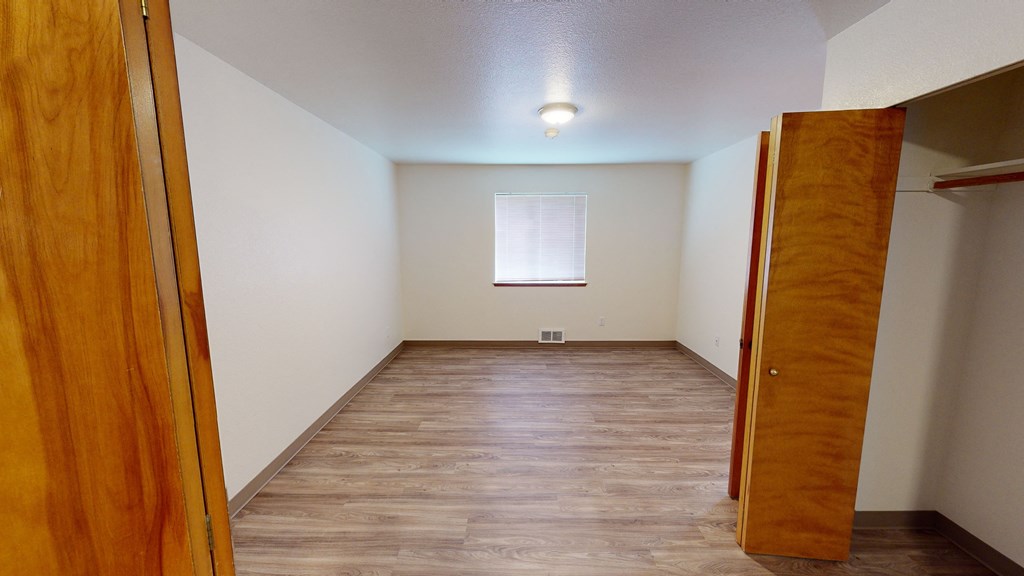 a room with a wood floor and a window and a wooden door