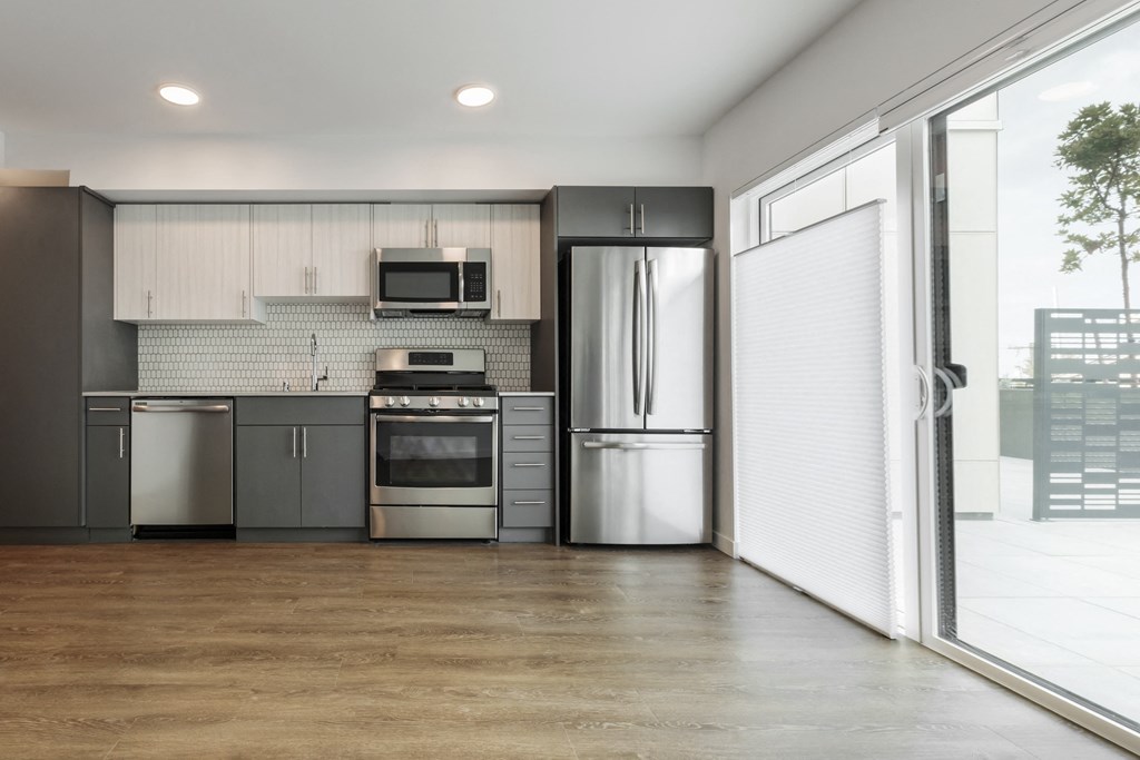 an empty kitchen with stainless steel appliances and a window