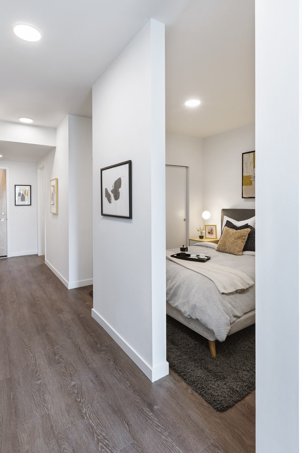 a bedroom with white walls and a bed in a room with wood flooring