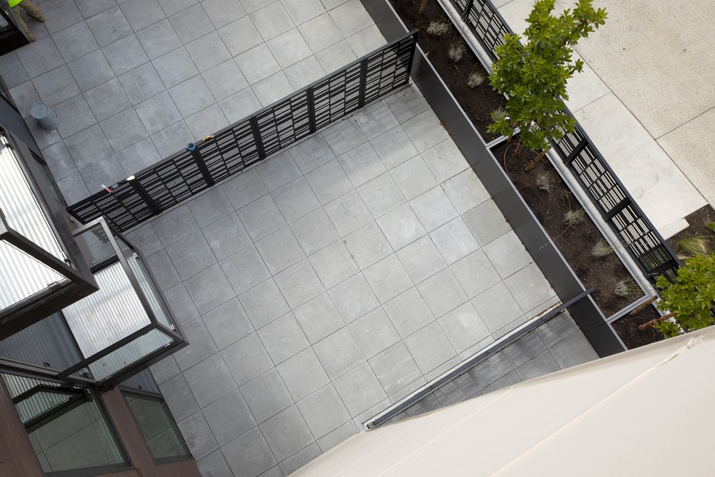 an overhead view of a courtyard with tiles and a metal fence