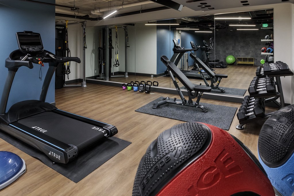 a gym with treadmills and other exercise equipment on a wooden floor
