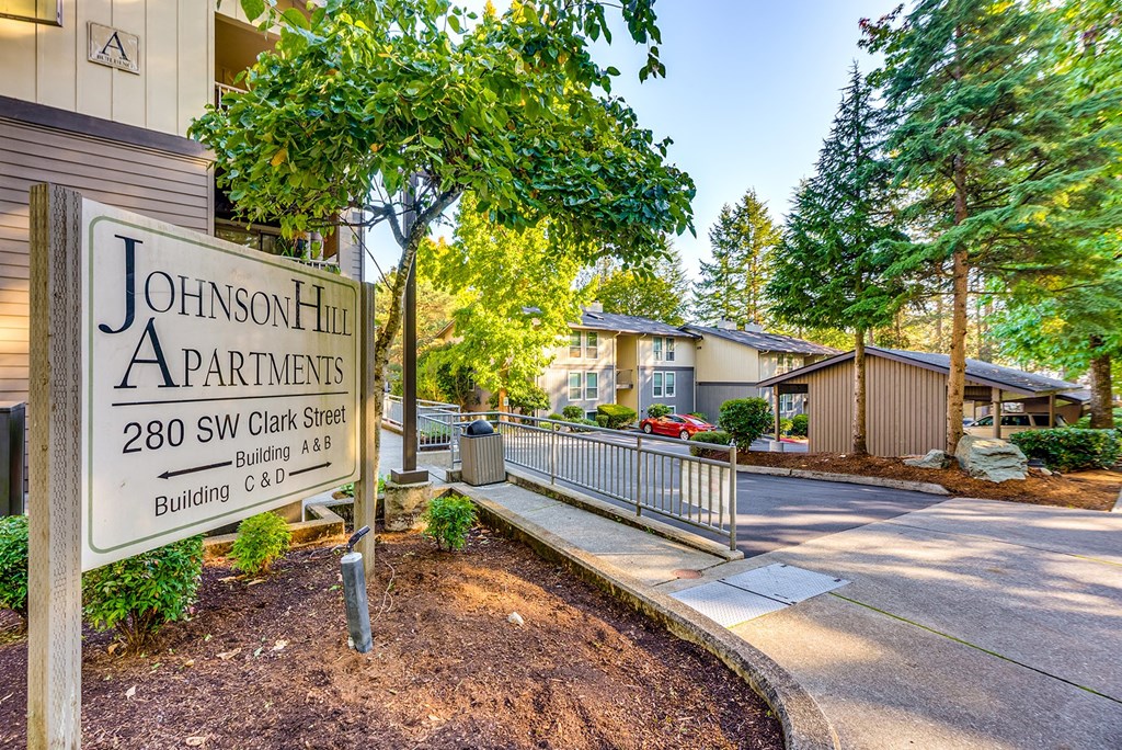 A sign for Johnson Hill Apartments is in front of a building.