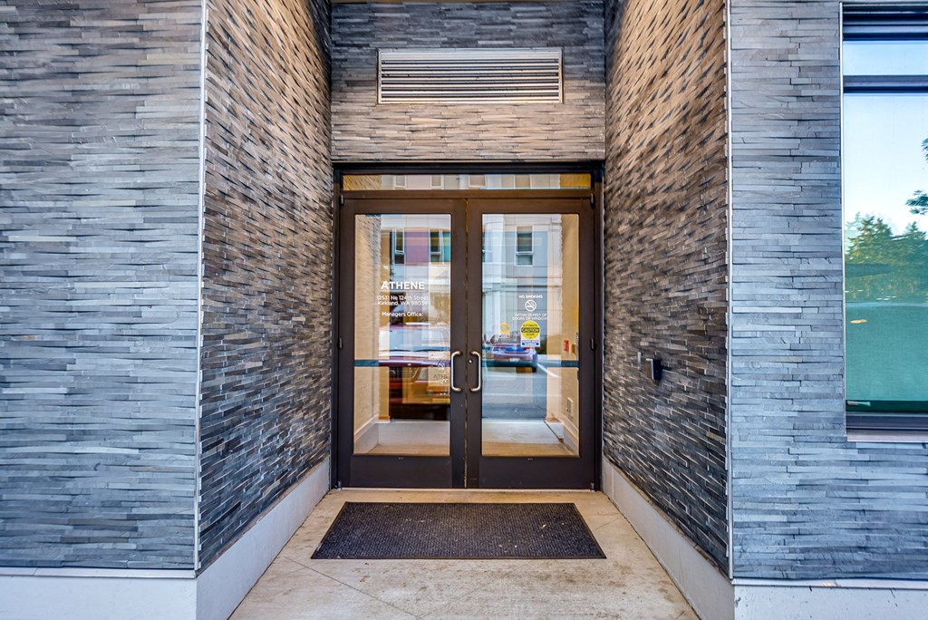 A modern building entrance with a glass door and a brick wall.