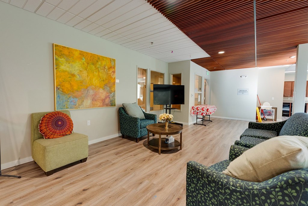 A living room with a green chair and a painting on the wall.