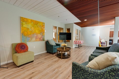 A living room with a green chair and a painting on the wall.