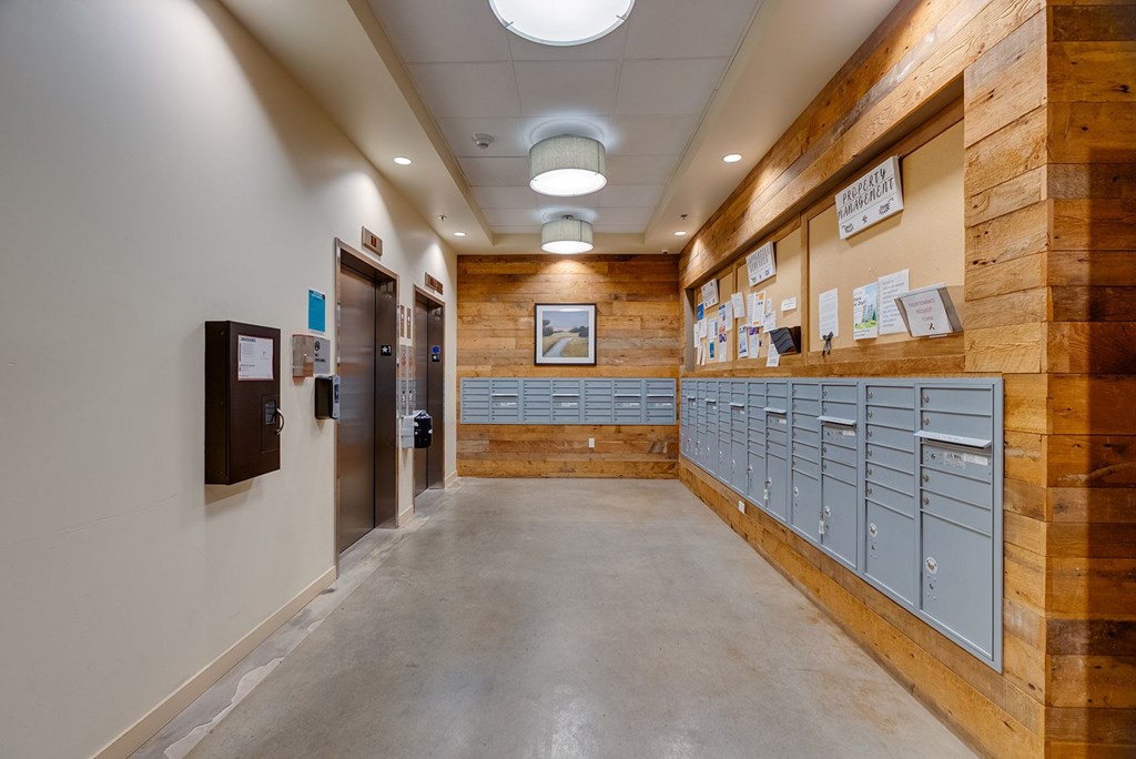 A long hallway with a wood panelled wall and metal lockers.