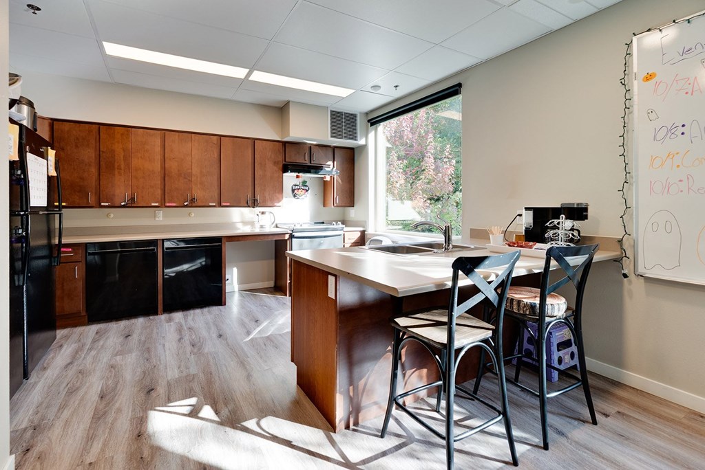 A whiteboard with writing on it sits in a kitchen with a table and chairs.