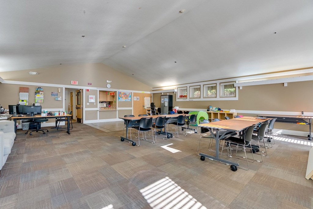 A room with tables and chairs and a whiteboard on the wall.
