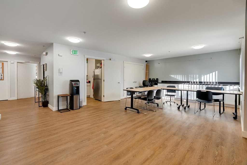 A room with tables and chairs and a white exit sign on the wall.