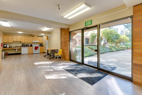 A kitchen area with a dining table and chairs is visible through a glass door.