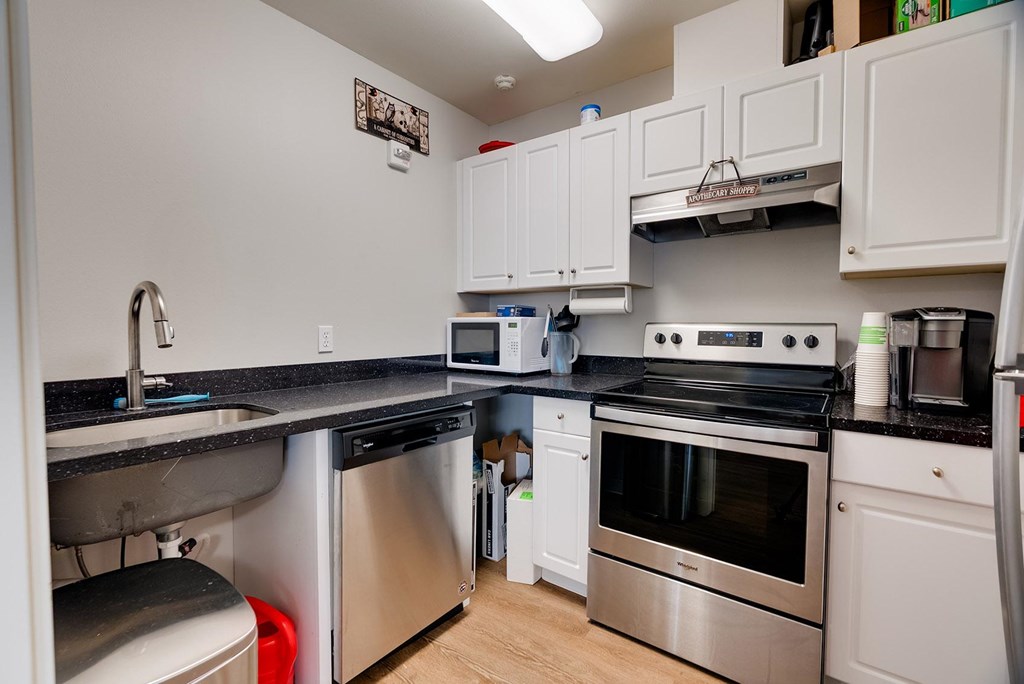 A kitchen with white cabinets and black countertops.