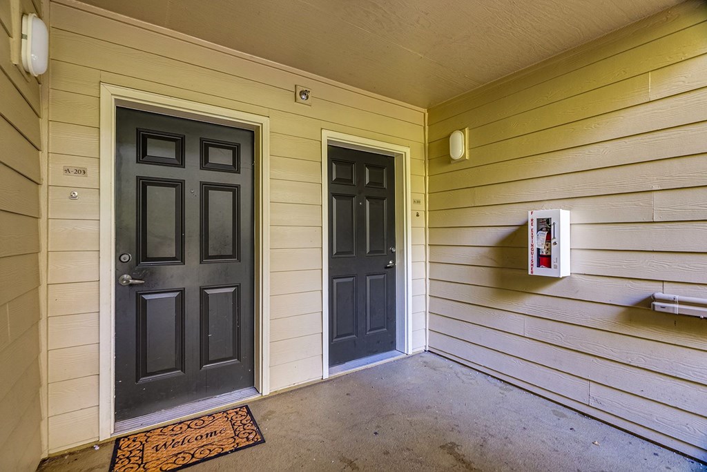 A hallway with two doors and a doormat that says "Welcome".