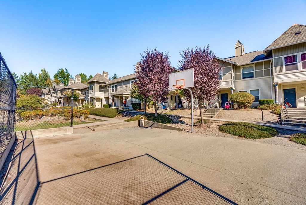 A basketball court is surrounded by a fence and apartment buildings.