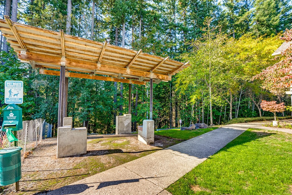 A wooden structure with a roof is in the middle of a grassy area.