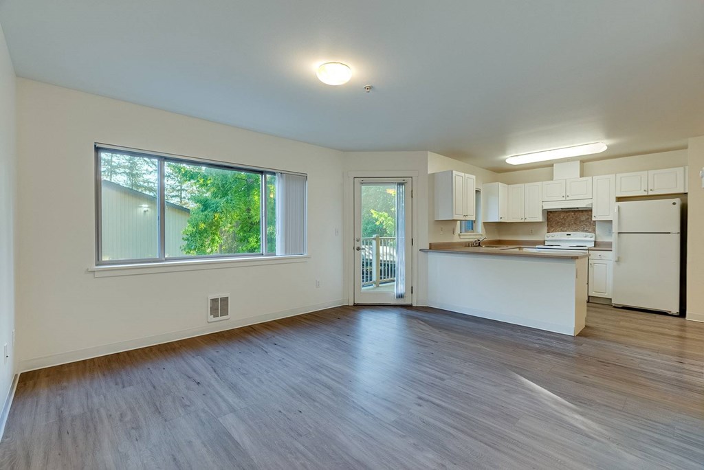 A spacious living room with a kitchen area in the background.