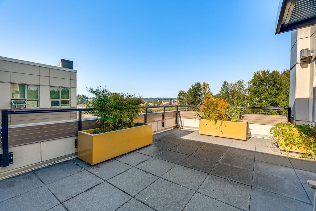 A rooftop patio with a yellow planter box and a balcony railing.