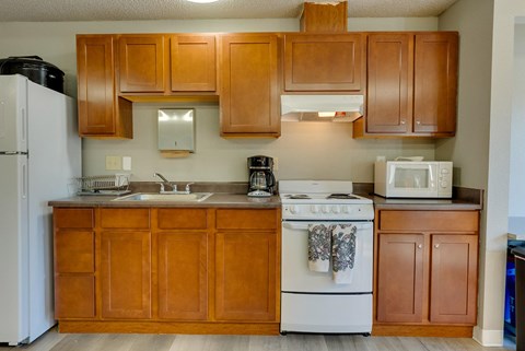A kitchen with wooden cabinets and a white stove.