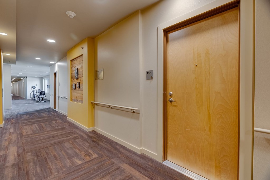 A hallway with a wooden floor and a wooden door.