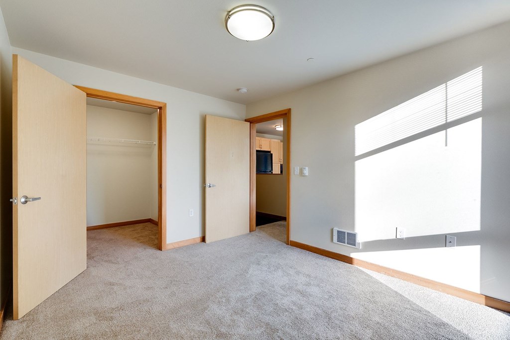 A room with a carpeted floor and three doors.