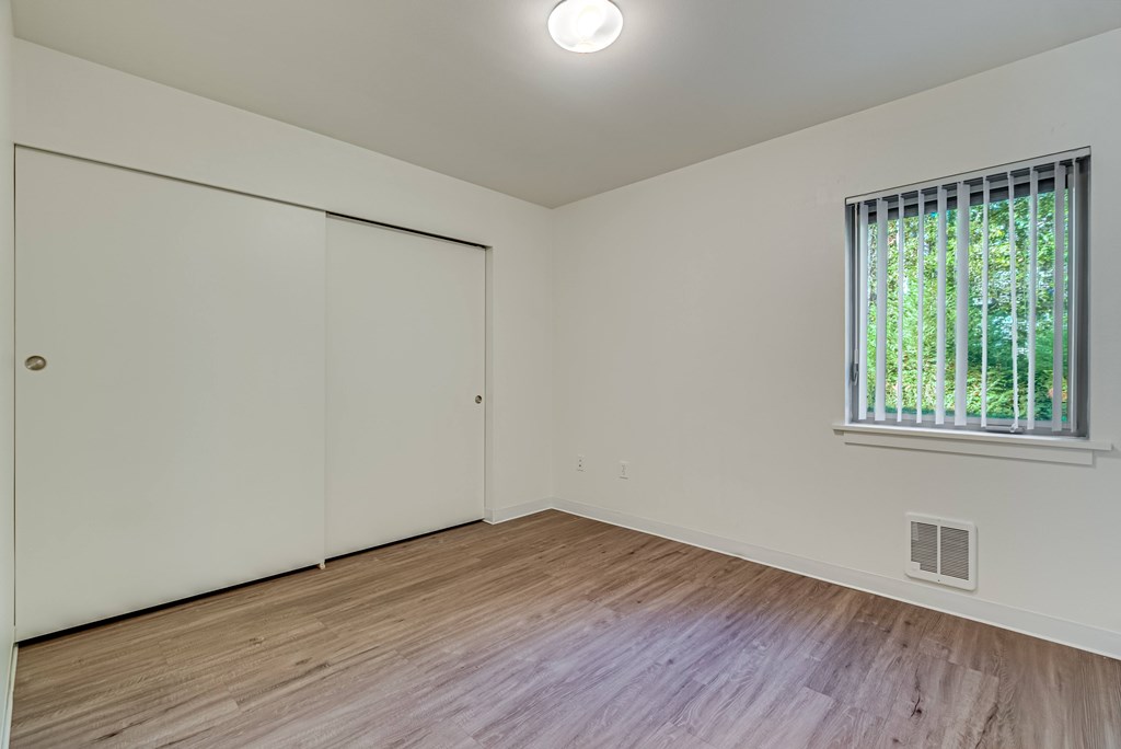 A room with a sliding door, a window, and a wooden floor.