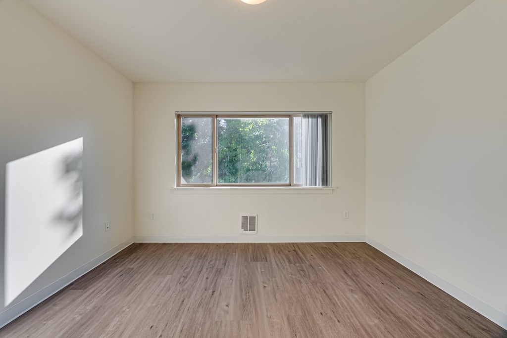 A room with a window and wooden flooring.