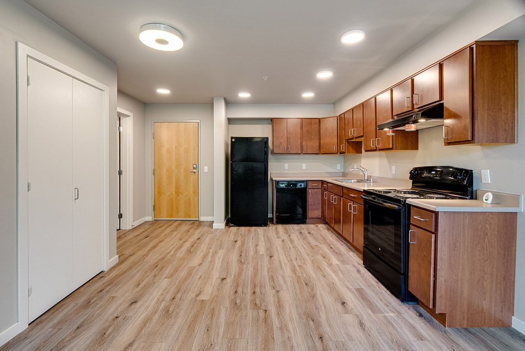 A kitchen with wooden floors and black appliances.