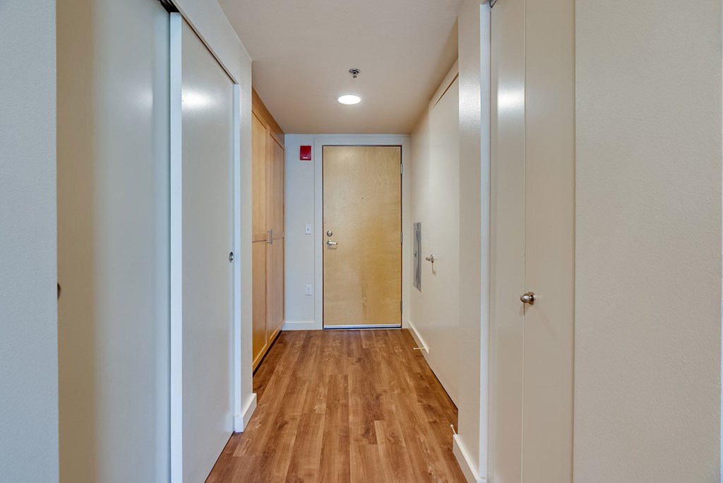 A long hallway with a wooden floor and white walls.