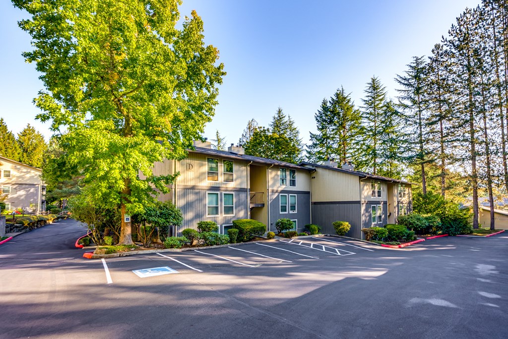 A parking lot in front of a building with trees on the side.