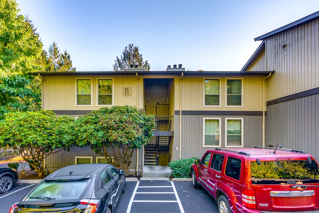 A red SUV is parked in front of a two-story house with a garage.