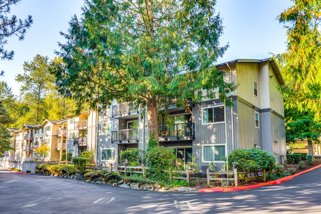 A row of modern townhouses with balconies and trees in the background.