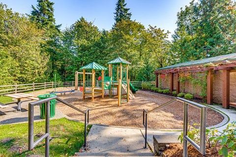 A playground with a green canopy and a slide.