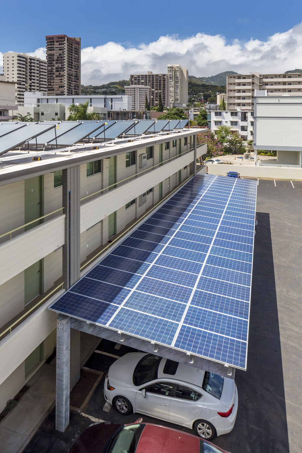 A parking lot with solar panels on the roof and cars parked.
