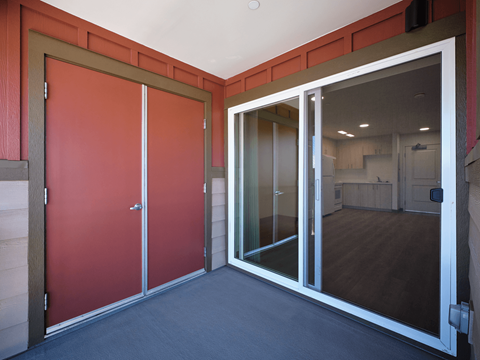 A room with a red door and a glass door leading to another room.