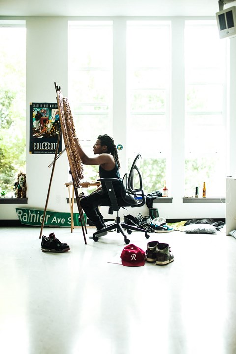 a woman sits in a chair in front of a easel and paints