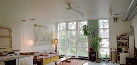 A living room with a couch, a table, a potted plant, and a painting on the wall.
