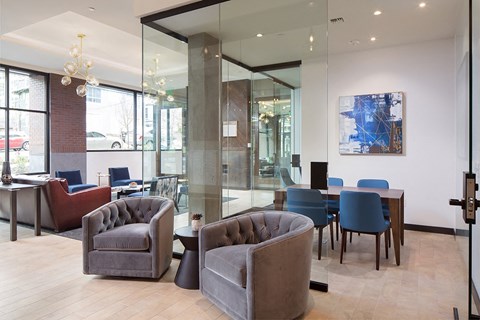 a lounge area with chairs and tables in a room with glass walls